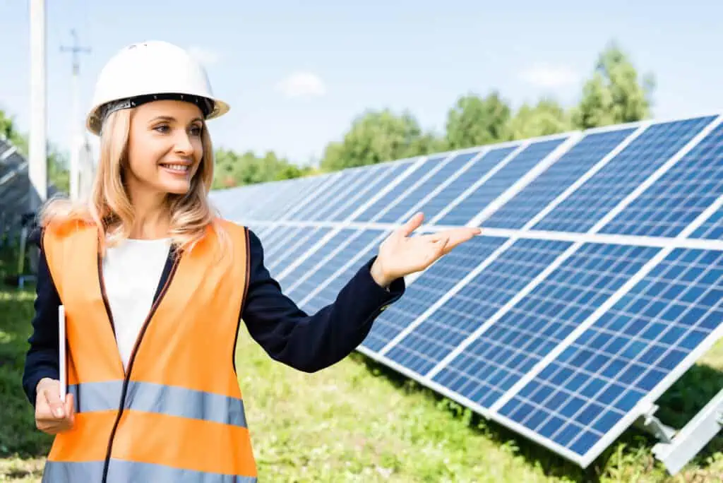 Woman pointing to solar panels and teaching the benefits of using solar energy to replace fossil fuels.