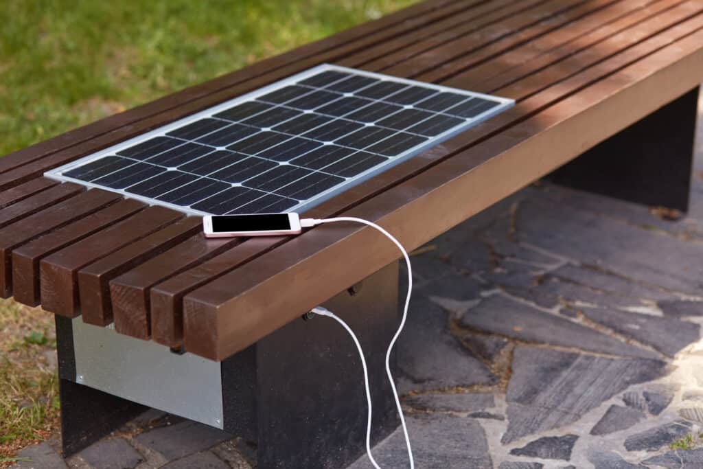 Bench with a built-in solar panel that's charging a phone battery.