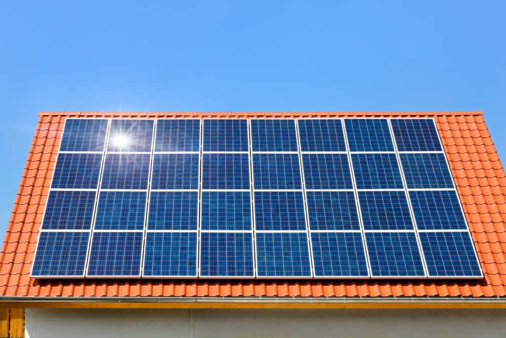 Solar panels on roof under clear blue sky showing the role of sunlight in solar energy production.